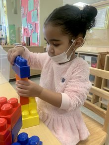 Children Center student Abigail playing with blocks.